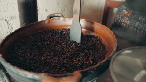 Woman's-Hand-Roasting-Coffee-In-A-Big-Pot-In-Guatemala,-Central-America---close-up