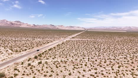 Drone-following-a-car-while-rotating-slightly-driving-on-a-long-desert-road-in-4k