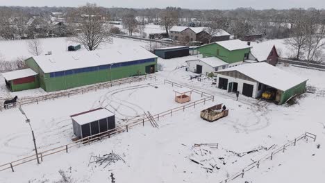 Vista-Aérea-De-Una-Granja-Nevada-Con-Caballos-En-El-Norte-De-Alemania.