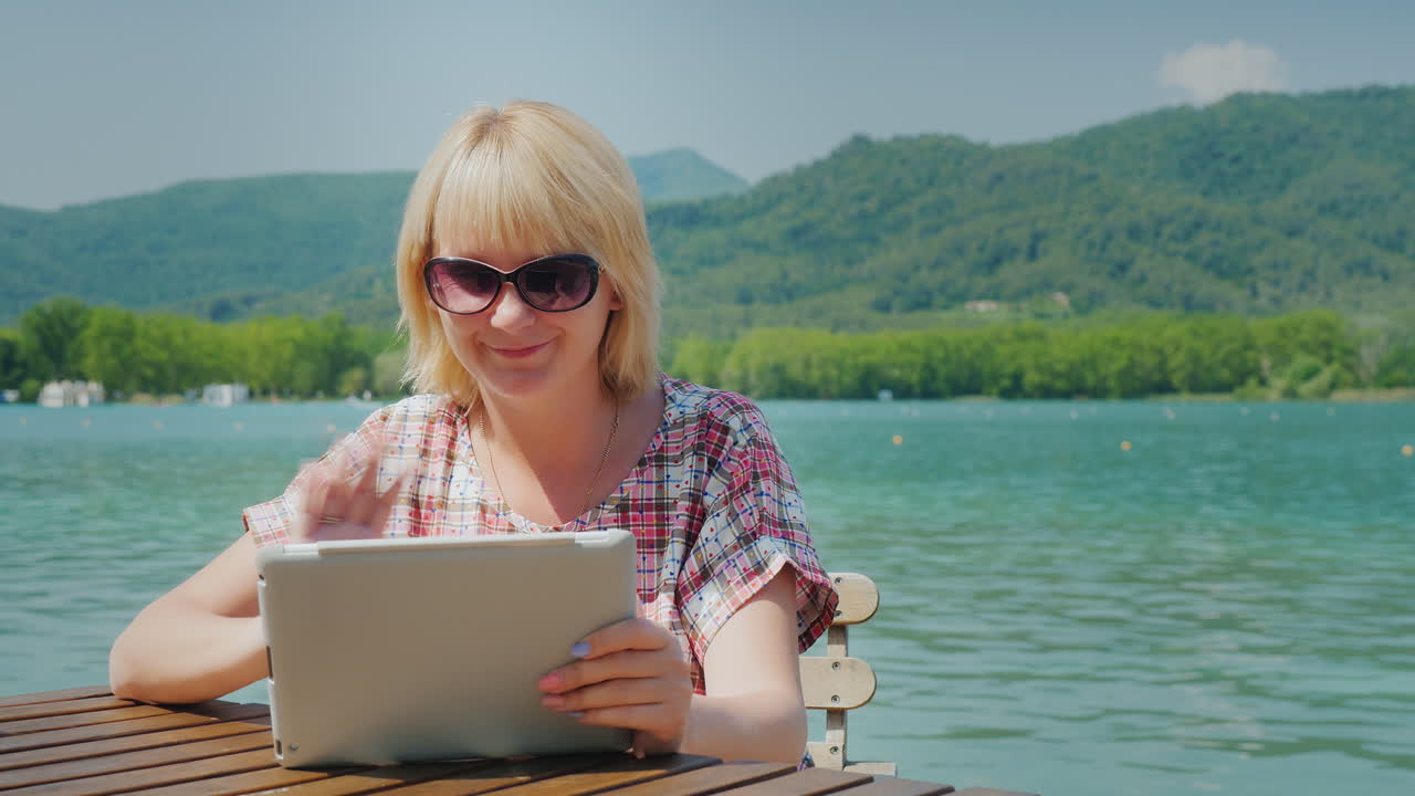 비디오 연결로 접시를 통해 항상 연결된 젊은 여성 obschaetsya는 backgro에 앉아