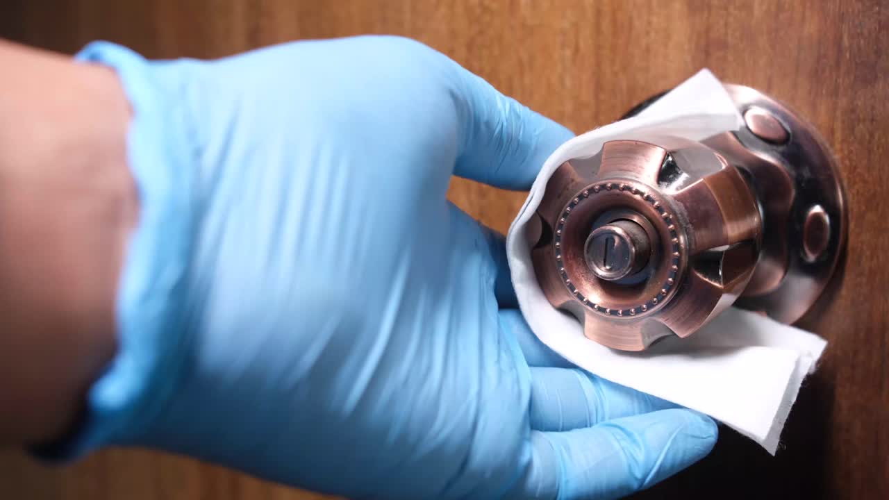 limpieza de una manija de la puerta con guantes