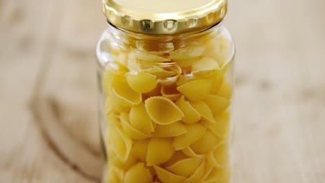 conchiglion pasta in jar clossed by its lid on wooden table