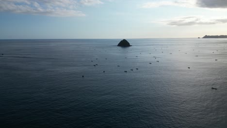 A-small-island-isolated-in-the-sea-and-surrounded-by-boats-off-the-coast-of-Lombok,-Indonesia