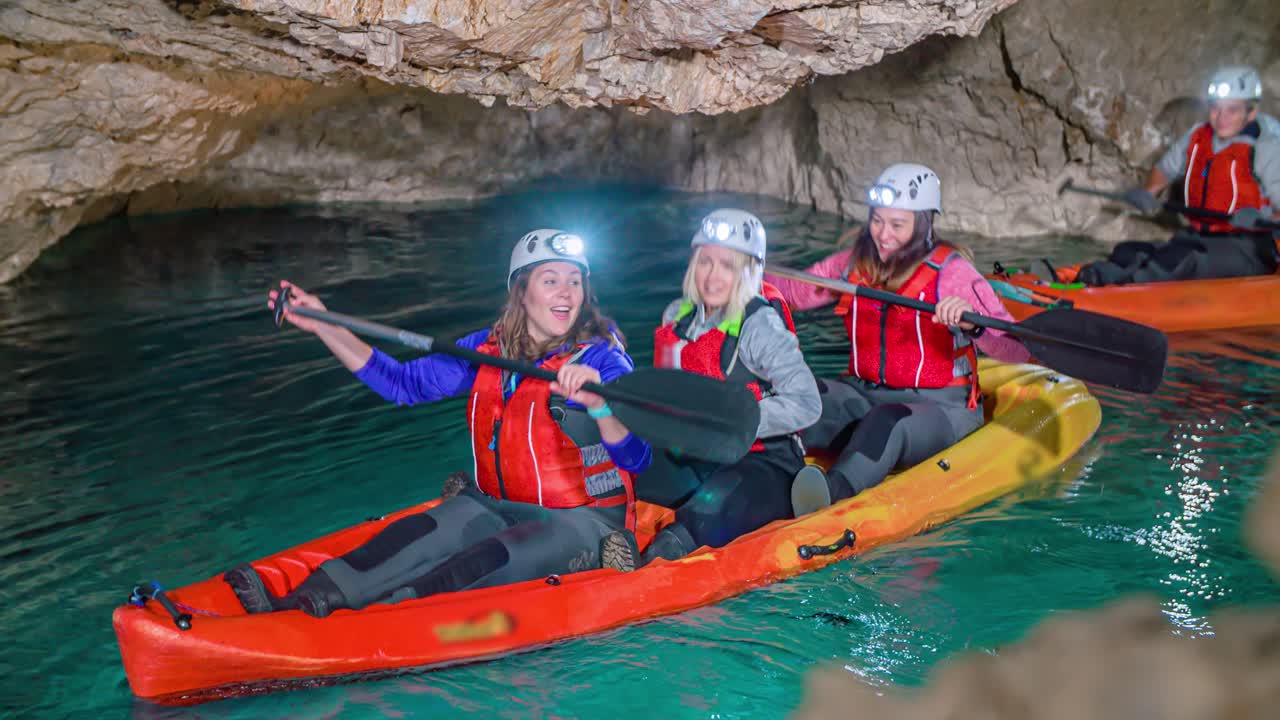 Group of young women in kayak experiencing unique adventure in cave