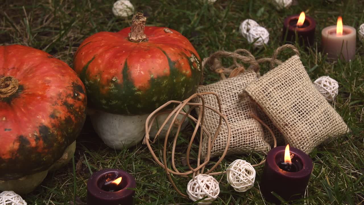 fondo otoñal con calabazas y velas con llamas moviéndose en el viento