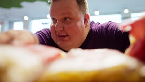 an interested overweight man in a purple t-shirt sorts out bags of goodies on the counter. happy man choosing snacks in a supermarket