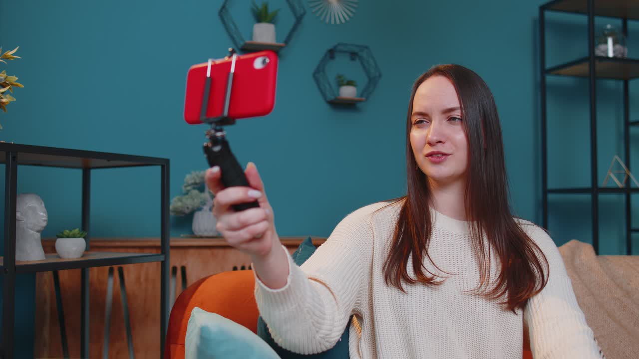 Girl blogger influencer taking selfie on smartphone make virtual social media video online at home