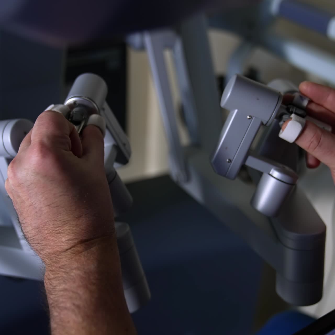 Doctor operating the robotic equipment with the help of master manipulators. Male hands move slowly the motion controllers. Close up