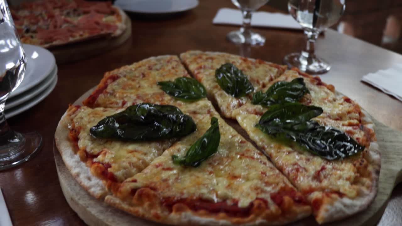 Handheld shot of a six-slice cheese pizza with basil leaves on top