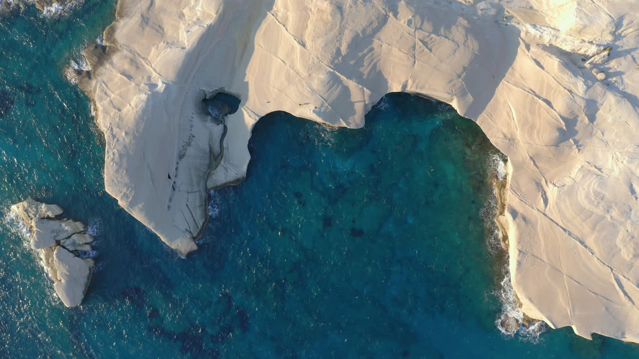 aerial: vista de arriba hacia abajo de la playa de sarakiniko en la isla de milos, cícladas, grecia durante el amanecer
