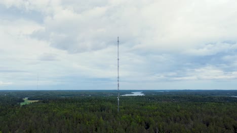 tall cell tower surrounded by woods on a cloudy evening