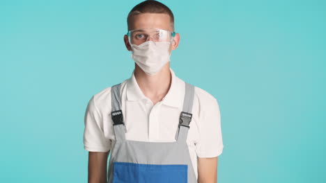 joven constructor en uniforme, máscara facial y gafas de protección