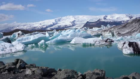 icy glacial lagoon with floating icebergs under blue sky in iceland, clear reflection on water