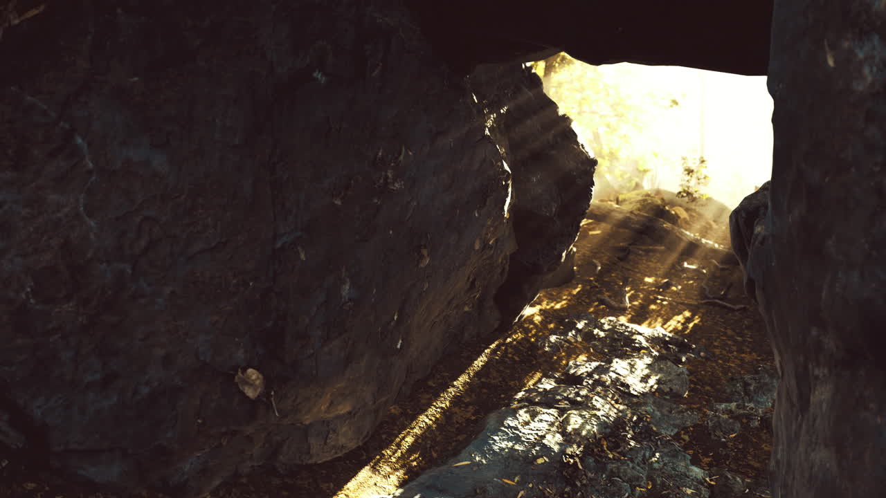 Light streaming through a rocky cave revealing a serene landscape