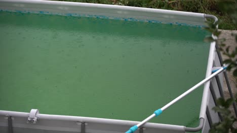 raindrops on surface of water in pool. close-up. green water in swimming pool. heavy rain. splashes from raindrops.