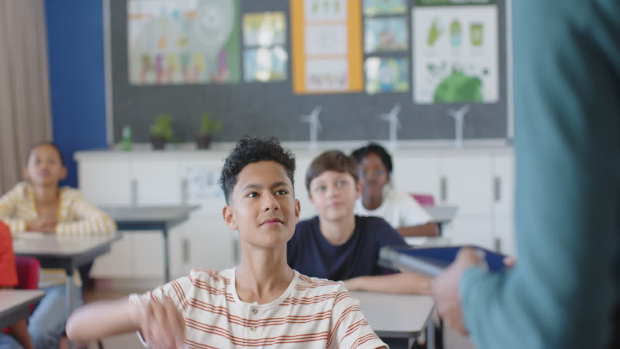 In school, boy raising hand in classroom, engaging with teacher