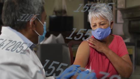 Animation-of-rising-numbers-with-masked-male-doctor-giving-vaccination-to-woman