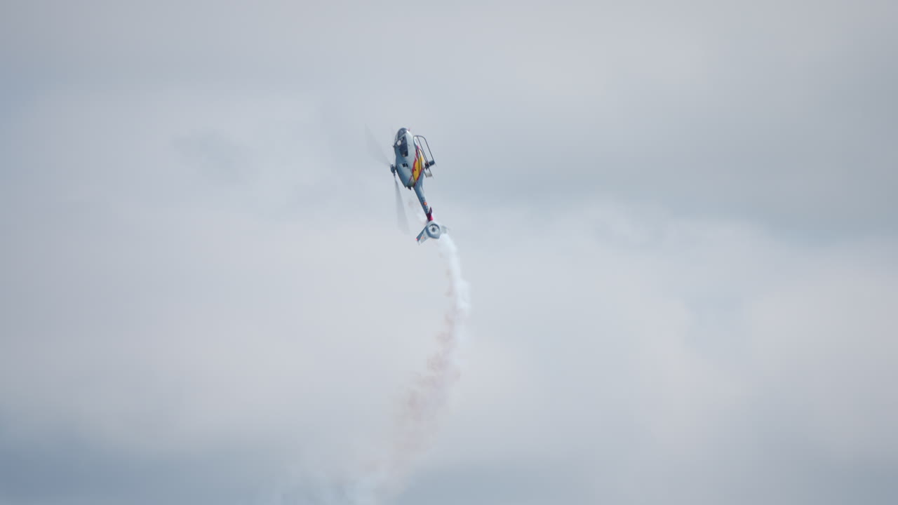 Single helicopter flying in spiral pattern during aerobatic stunt with smoke trail