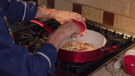 cebollas picadas siendo vertidas en una sartén caliente para saltearlas en cámara lenta