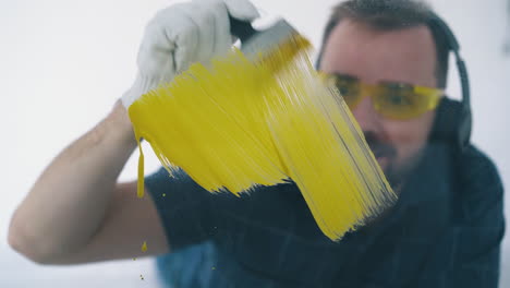 young man with goggles paints wall with yellow color in room