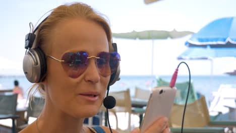 una mujer con auriculares hablando en video en su móvil.
