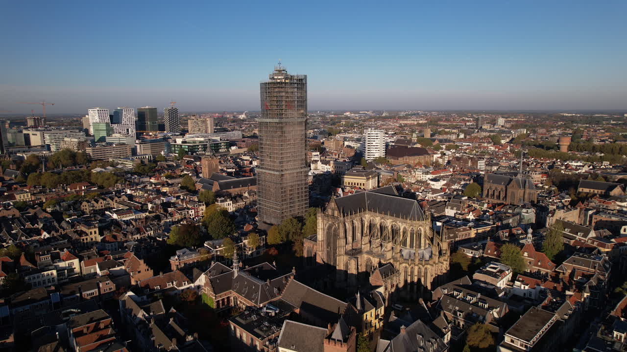 교회의 나머지 부분에 대한 건축학적 세부 사항과 함께 도시 경관 위로 우뚝 솟은 위트레흐트(utrecht)의 네덜란드 도심에 있는 스캐폴딩에 있는 중세 대성당 탑에 닫힙니다.