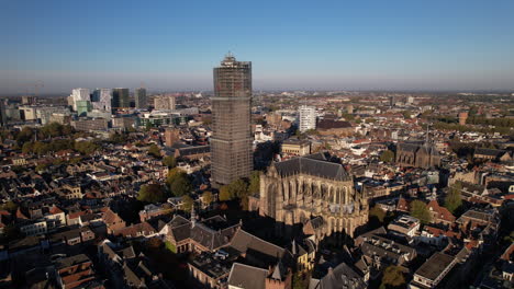 closing in on de dom medieval cathedral tower in scaffolding in dutch city center of utrecht towering over the urban cityscape with architectural details of the remaining body of the church