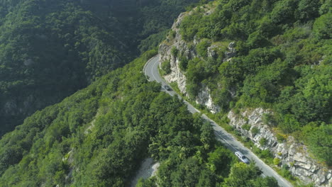 following black car on beautiful mountain road with rocks on the side