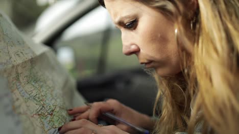 conductor escribiendo en un mapa de papel en el coche durante el viaje