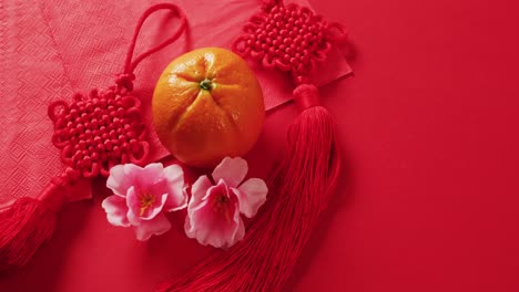 Video-of-close-up-of-orange-and-decorations-on-red-background