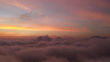 The-beautiful-fiery-orange-sunset-view-above-the-clouds-of-Bali,-Indonesia---Aerial-shot