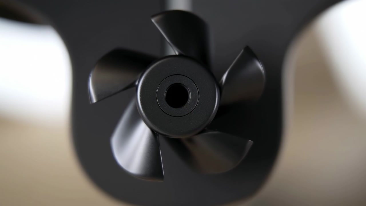 Close-up centralizado de um rotor escuro giratório ou pá de ventilador com desfoque de movimento circular, em um fundo suave e desfocado e destacando o aspecto mecânico.