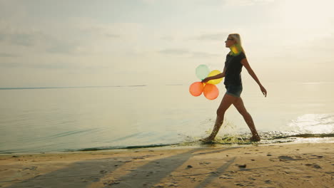Carefree-Young-Woman-Walks-Along-The-Beach-In-The-Beautiful-Sky-Is-Holding-Balloons-Slow-Motion-Vide