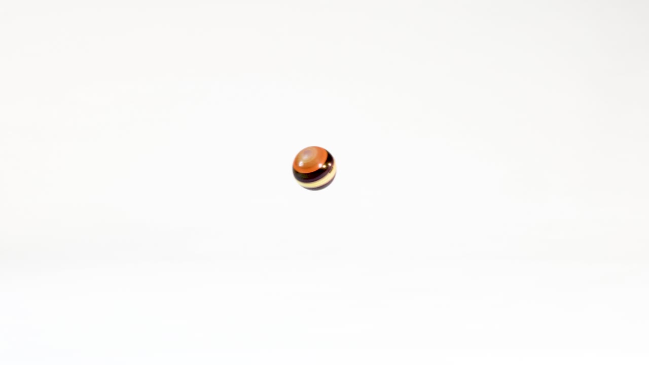 A small brown striped wooden ball bounces across a bright white studio background
