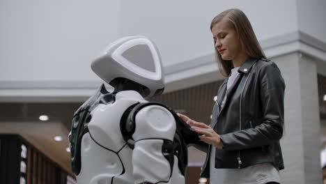 happy woman in contact with cyborg robot. click on the robot screen. a droid interacts with a woman