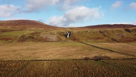 waterfall in the middle of mountains surrended by fields in scotland