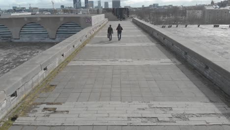 two people walking on a city bridge