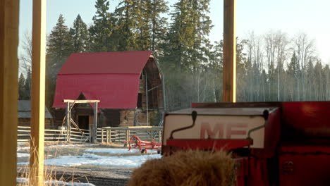 view of quaint red barn through farm machinery