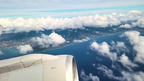 plane flying by island with aircraft wing and engine seen from the window of an airplane