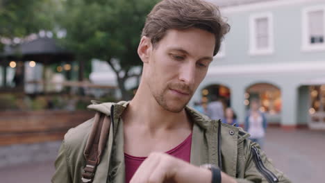 portrait of handsome young man looking at wrist watch on busy urban background