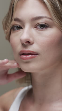 vertical video of caucasian woman with blond hair touching face, copy space, slow motion