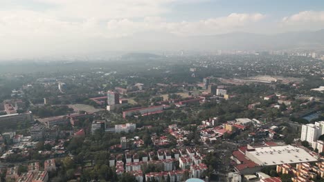 Dron-Despegando-Con-Una-Vista-Del-Sur-De-La-Ciudad-De-México,-Con-La-Ciudad-Universitaria-Al-Fondo