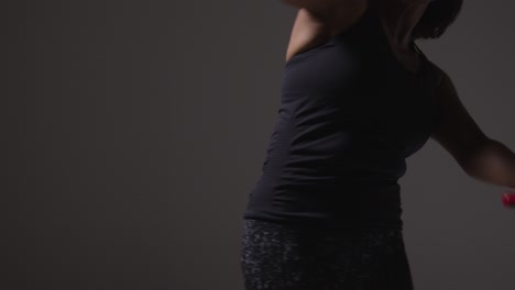 fotografía de estudio de cerca de una mujer madura con ropa de gimnasia haciendo ejercicio con palos de artes marciales escrima