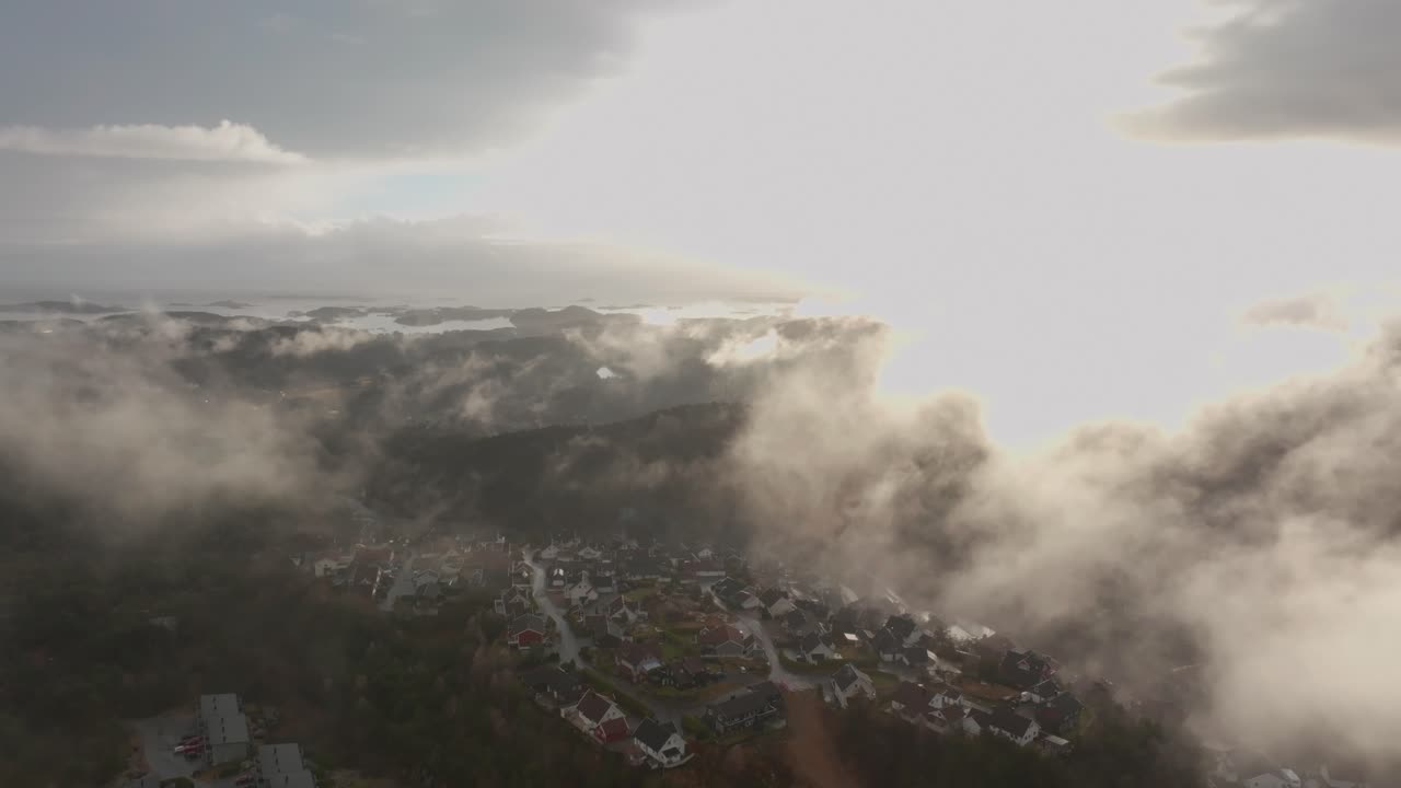 съемка с дрона жилого комплекса в норвегии с туманом в воздухе и солнцем, освещающим облака