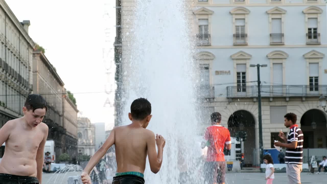 Kids having fun and  refreshing in a fountain through the streets of Turin to take off the heat wave.