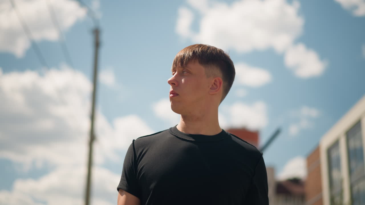 구름으로 가득한 화창한 도시의 수평선을 올려다보는 십 대 모험가, 밝고 드넓은 대도시의 하늘과 구름을 바라보는 젊은 개인의 활기찬 여름 풍경