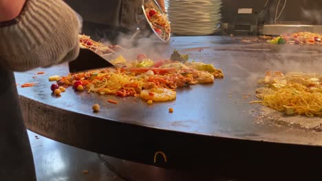 Chef-Playing-Skillful-Tricks-while-Stir-Frying-on-a-Large-Stove-at-a-Mongolian-Grill