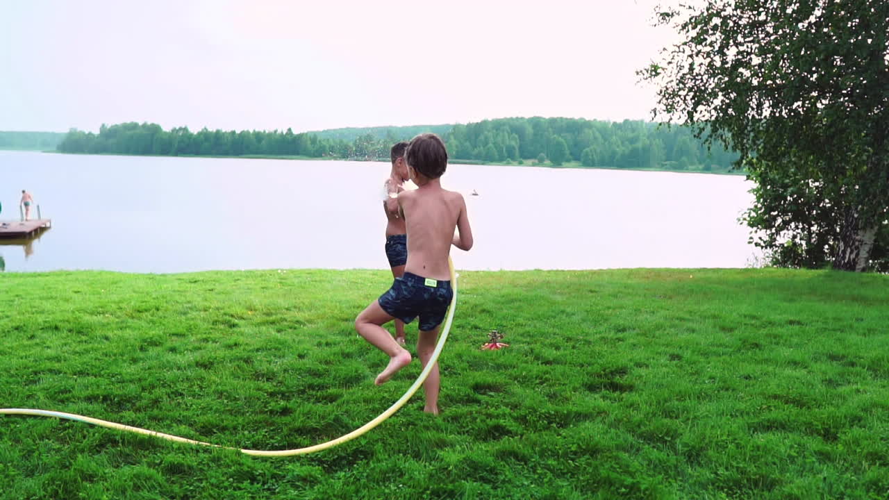 두 소년은 집 뒷마당에서 엄마와 아빠와 함께 놀고 있습니다. 호스 물로  ⁇ 고 슬로우 모션으로 웃고 웃고 있습니다. 행복한 가족