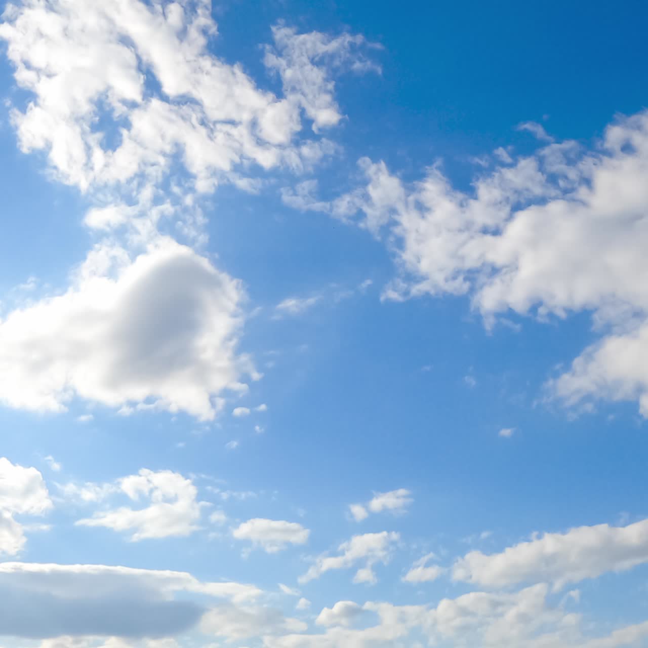 Stunning azure sky with brightly shining sun and soft cloudscape. White fluffy clouds quickly changing shapes in the atmosphere. Timelapse