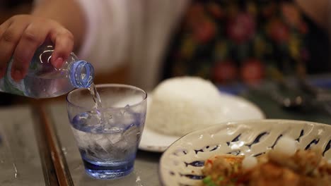 water being poured into a glass with ice